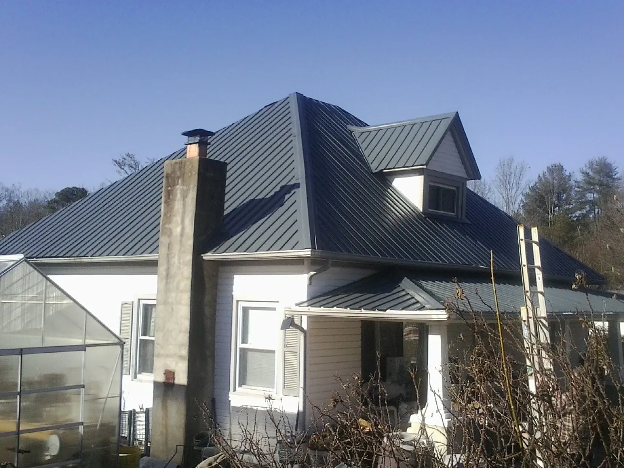 Dark blue standing seam metal roof on a white farmhouse with dormer — Slate & Tile Roof Repair by Roofing Brothers in Ralph