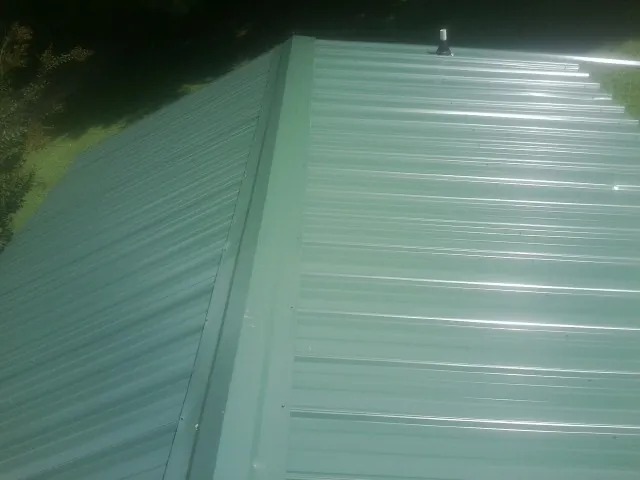 New green metal panels meeting at the ridge of a roof — Flat Roof Repair work by our crew in Ralph