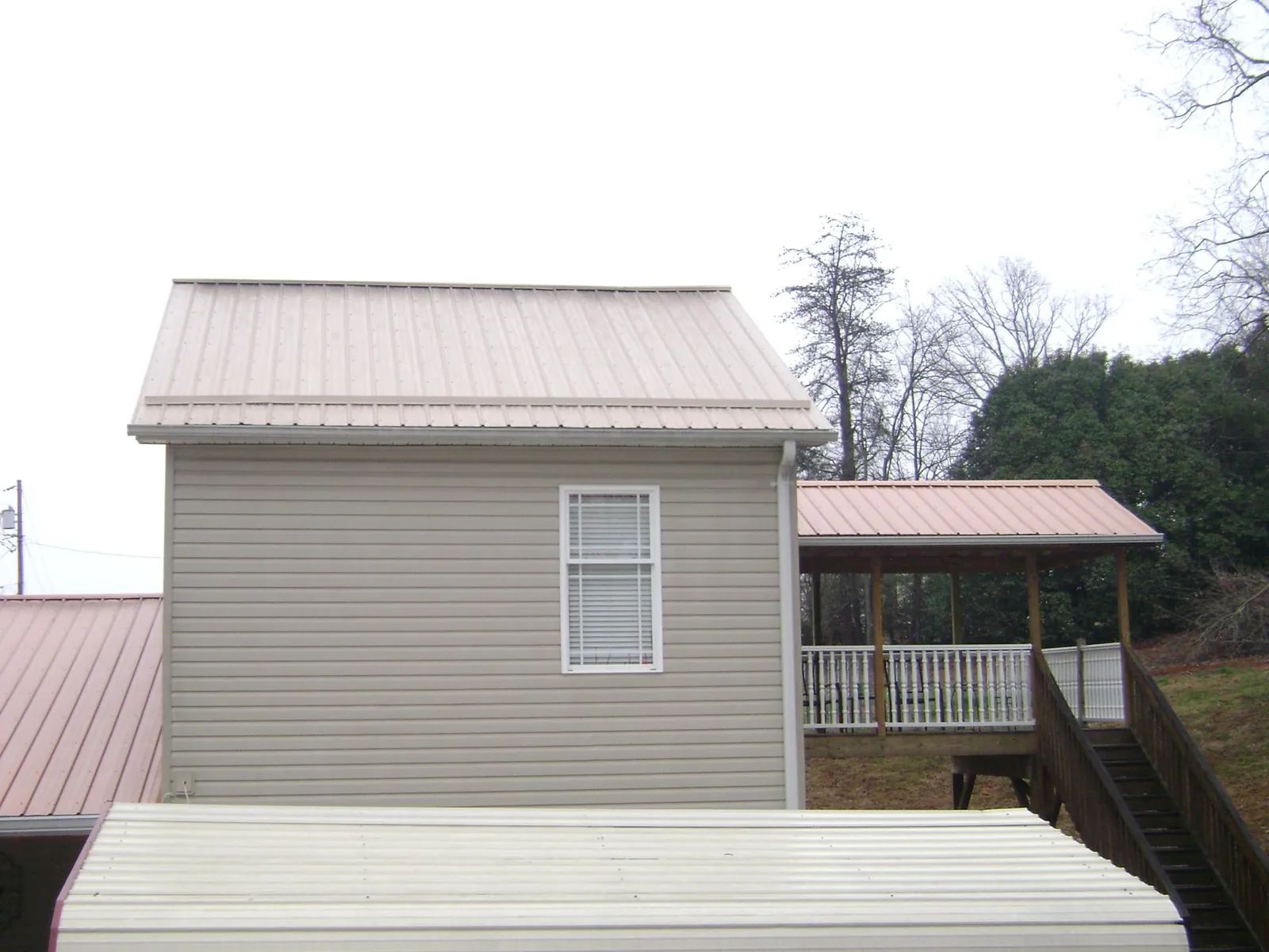 Tan metal roofs on a two story addition and attached porch, from a Roof Replacement job in Ralph